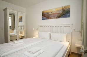 A hotel room with a bed, two bedside tables, a wardrobe, and a painting on the wall. - Die Ferienwohnung Nr. 06 in der Villa Karola - Villa Karola (Göhren)