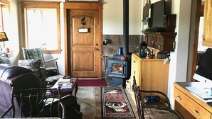 A cozy living room with a fireplace, wooden furniture, and a stone-tiled floor. - The Ultimate Escape  (Heron)