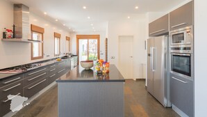 Una cocina moderna con una isla grande, electrodomésticos de acero inoxidable y vistas al exterior.