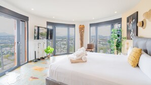 Habitación de hotel moderna con una cama grande, vistas a la ciudad y un amplio ventanal.