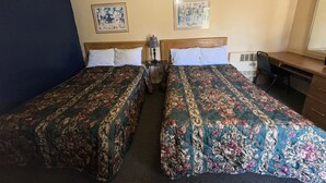 A hotel room with two beds, a desk, and a chair.