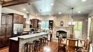 Una cocina amplia con una isla grande, taburetes de madera y una chimenea de piedra.