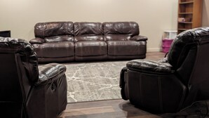A living room with a brown leather sofa, two leather recliners, a patterned rug, and a wooden bookshelf. - Hawk's Nest
Entire 1650 Sqft lower level.  (Moscow)