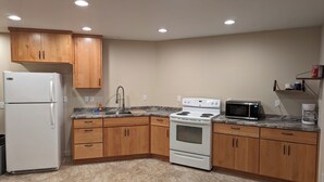 A kitchen with wooden cabinets, a white refrigerator, a stove, a microwave, and a coffee maker. - Hawk's Nest
Entire 1650 Sqft lower level.  (Moscow)