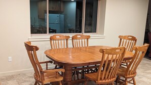 A dining area with a wooden table and chairs, a window with a view of a kitchen, and a tiled floor. - Hawk's Nest
Entire 1650 Sqft lower level.  (Moscow)