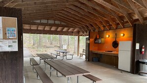Un espace pique-nique abrité, équipé de tables de pique-nique et d’une petite cuisine avec un fourneau et un réfrigérateur.