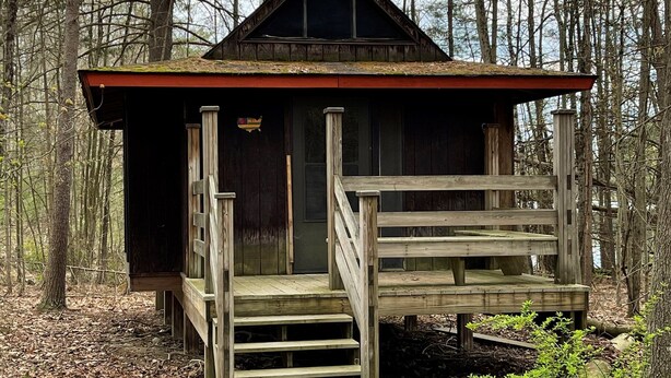 Un chalet rustique doté d’une terrasse en bois et d’un escalier menant à une porte.