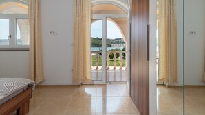 Une chambre avec un lit, un balcon offrant une vue et une porte-fenêtre coulissante.