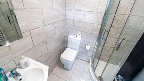 Un baño moderno con inodoro, lavamanos y cabina de ducha de vidrio.