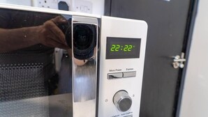 Eine Mikrowelle mit digitaler Anzeige, die 22:22 zeigt, einer Bedienblende mit den Tasten 'Micro Power' und 'Express' sowie einer 'Auftauen'-Einstellung.