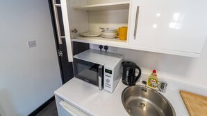 A compact kitchenette with a microwave, kettle, and sink. - Modern studio available close to the city (Birmingham)