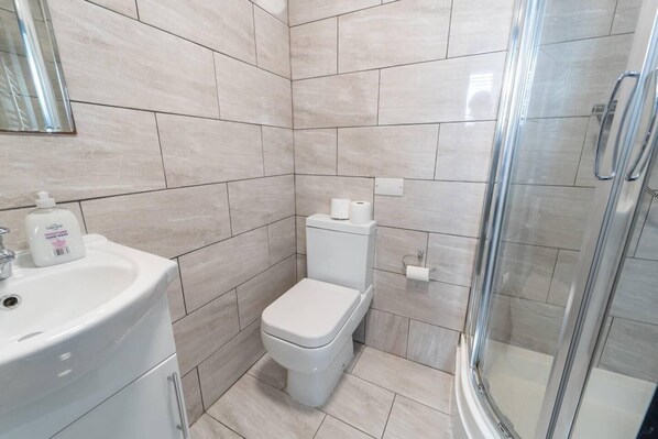 A modern bathroom with a toilet, sink, and glass shower enclosure.