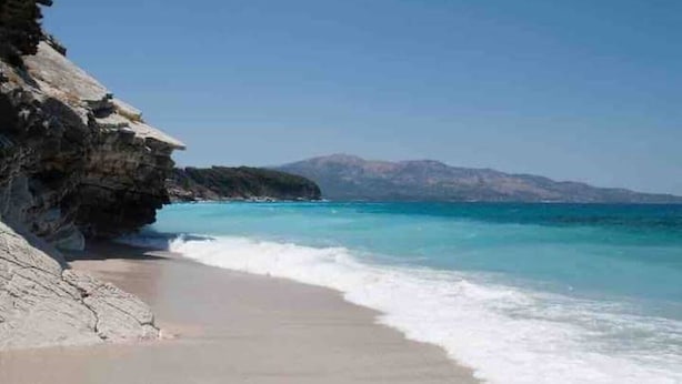 A beach with clear turquoise waters, a rocky cliff, and a distant mountain range. - Welcome to ILLYRIAN PARADISE. Near beach and Lake Views. (Ksamil)