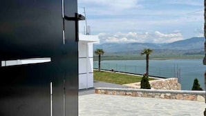 A modern building with a stone-tiled patio and a view of a lake and mountains. - Welcome to ILLYRIAN PARADISE. Near beach and Lake Views. (Ksamil)