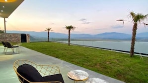 An outdoor seating area with chairs and tables, overlooking a body of water and mountains. - Welcome to ILLYRIAN PARADISE. Near beach and Lake Views. (Ksamil)