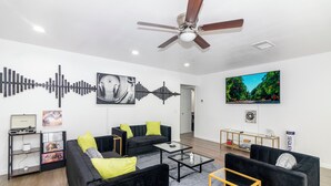 Un salon moderne avec des canapés noirs, une table basse en verre et un ventilateur de plafond.