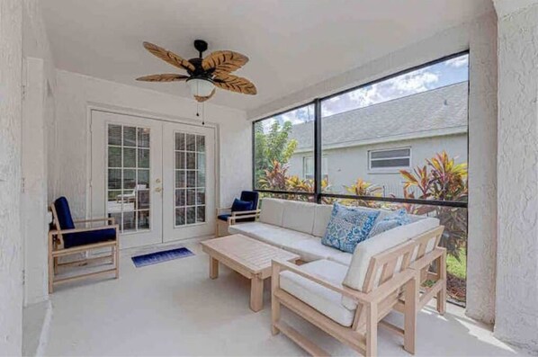 Relax in this serene room with a sofa, coffee table, and two chairs, offering a view of the surrounding residential area.