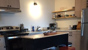 Una cocina moderna con una isla central, electrodomésticos de acero inoxidable y un horno empotrado.