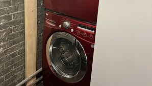 Lavadora y secadora roja, empotradas en la pared, con paneles de control y pantalla digital.