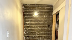 Un pasillo con pared de ladrillo, una mesa de madera y una lámpara colgante.