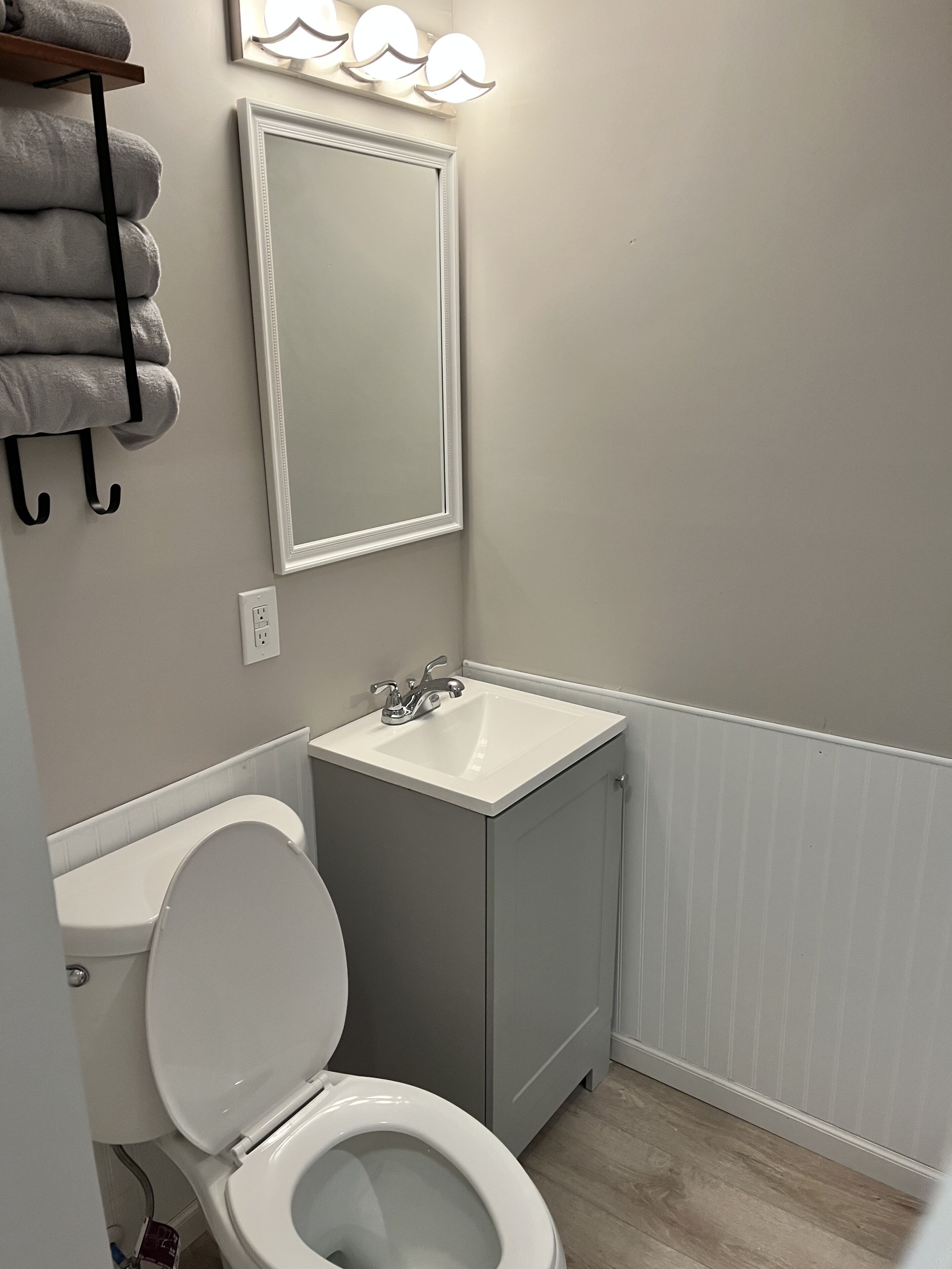 Een badkamer met toilet, wastafel en spiegel.