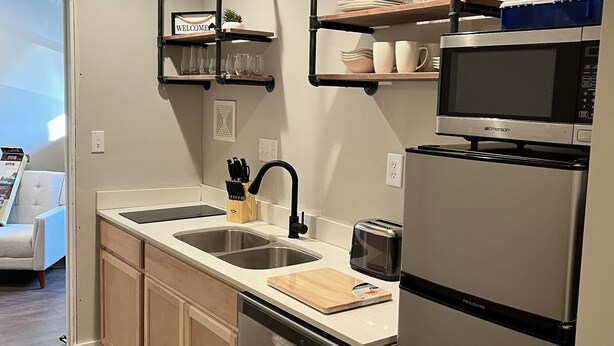 Una cocina moderna con electrodomésticos de acero inoxidable, armarios de madera y estantes empotrados.