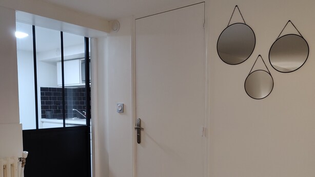 A hallway with a white door, a radiator, and a black gate. There are three wall-mounted mirrors. - L'escapade Enchantée Paris-disneyland (Noisy-le-Grand)