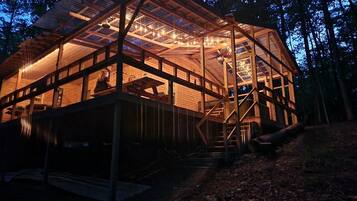 A wooden cabin with a glass roof, surrounded by trees.
