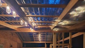A wooden cabin with a hot tub, wooden benches, and a sloped ceiling with exposed beams.