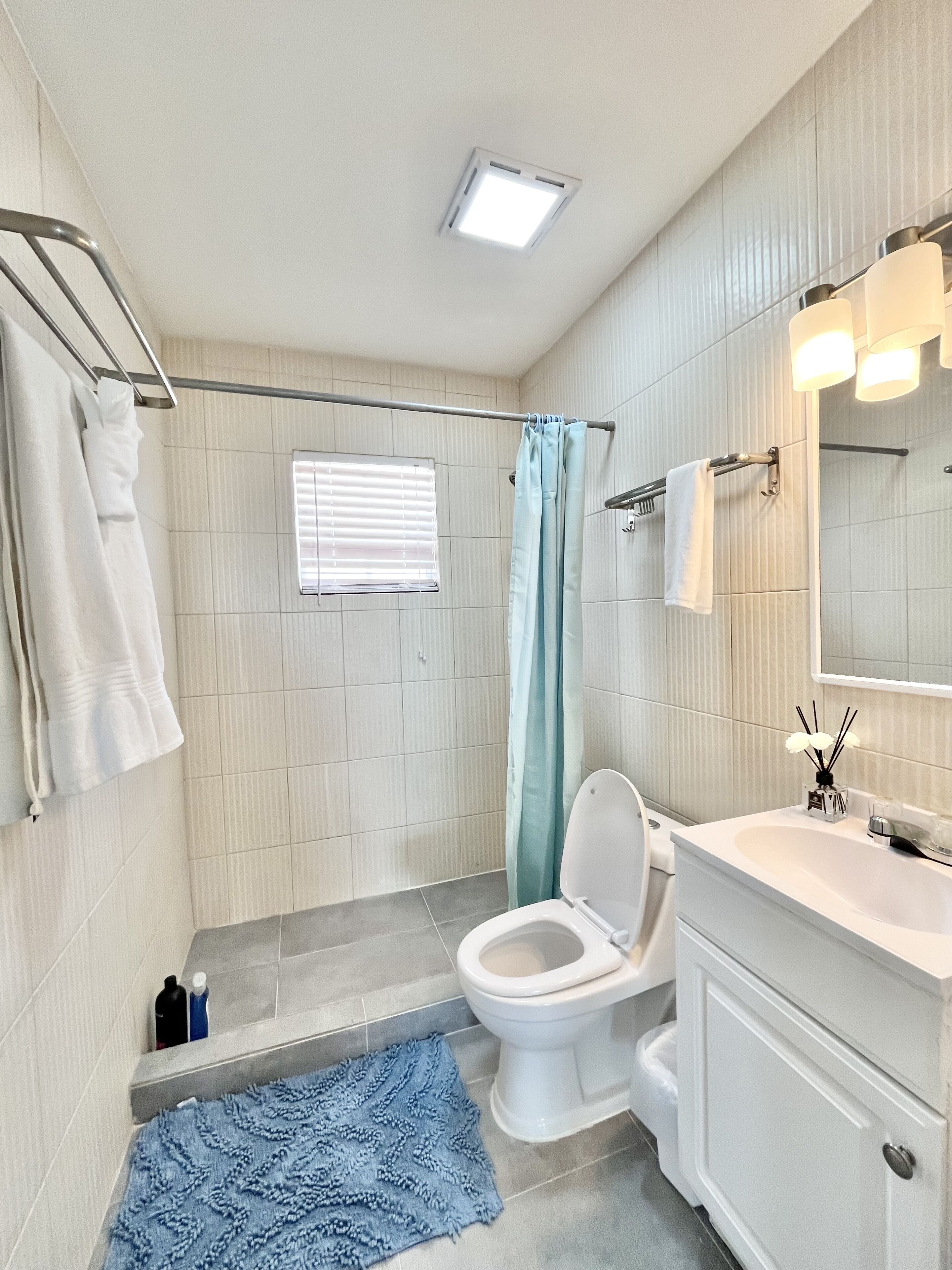 Een badkamer met douche, toilet, wastafel en een spiegel met verlichting.