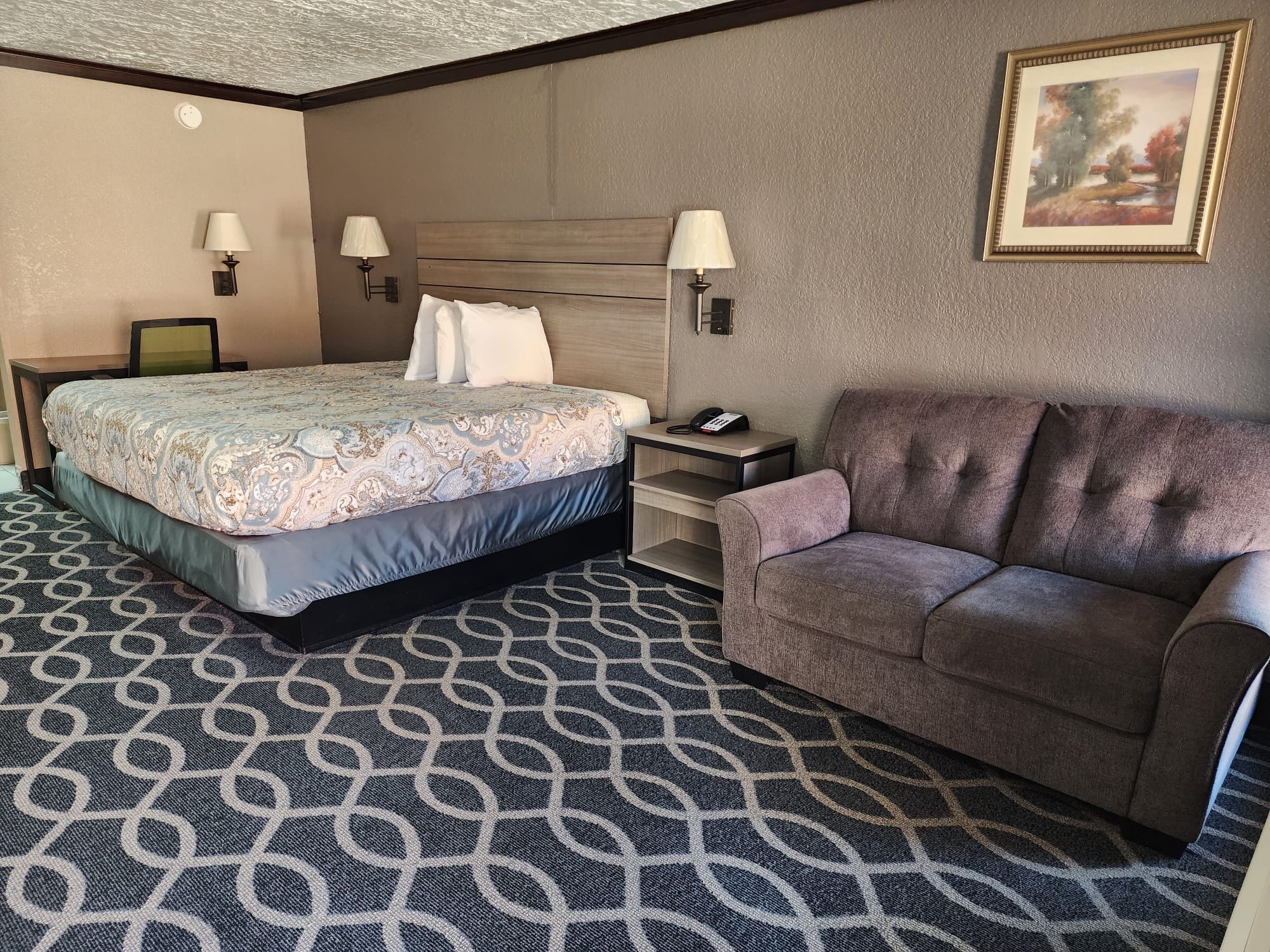 Ein Hotelzimmer mit einem Bett, einem Sofa, einem Schreibtisch und zwei Lampen.