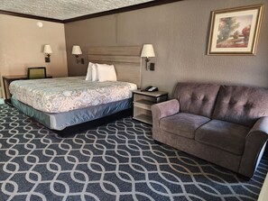 A hotel room with a bed, a sofa, a desk, and two lamps. - Executive Inn Oklahoma City NorthWest (Oklahoma City)