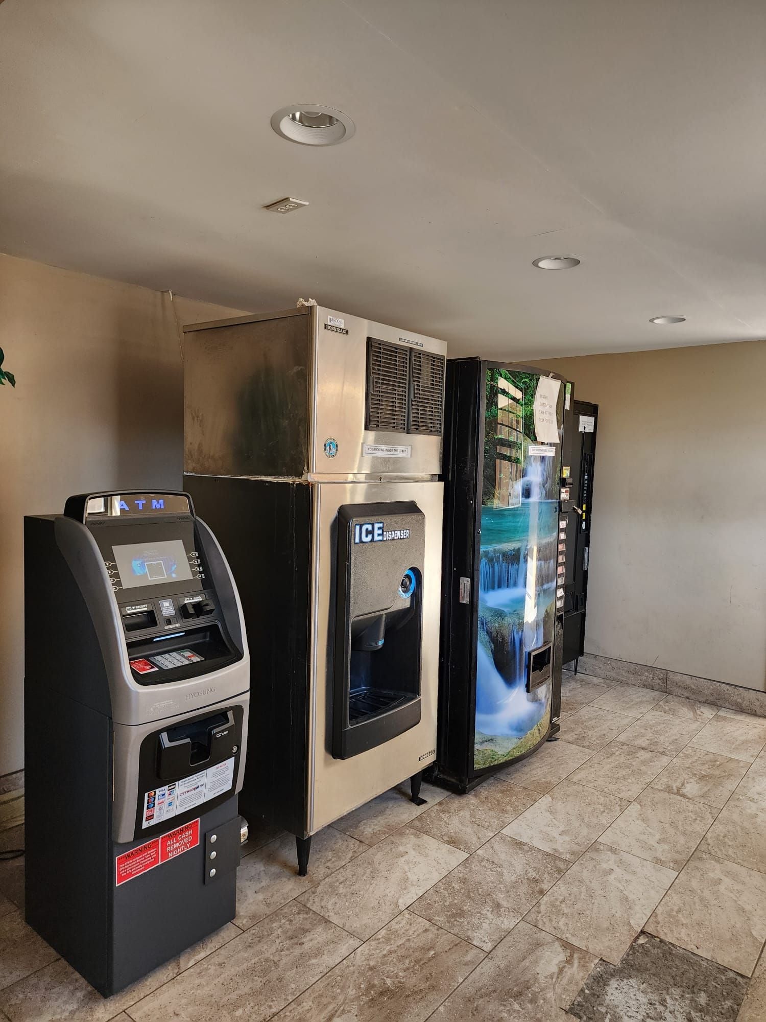 En hotellobby med en pengeautomat, minibar og vanddispenser.