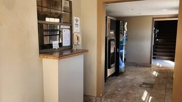 A hotel lobby with a reception desk, a phone, and a vending machine.