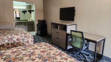 Une chambre d’hôtel équipée d’un lit, d’un bureau, d’une chaise, d’une télévision et d’un coin cuisine.