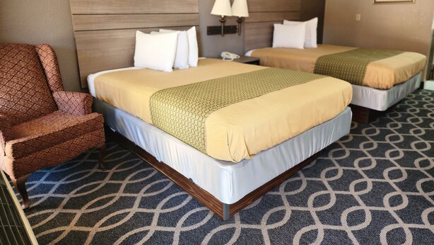 A hotel room with two beds, a chair, and a patterned carpet. - Executive Inn (Oklahoma City)