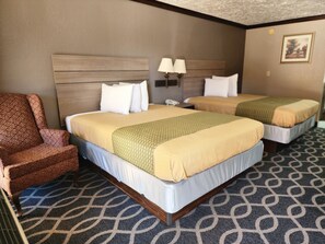 A hotel room with two beds, a chair, and a patterned carpet. - Executive Inn (Oklahoma City)