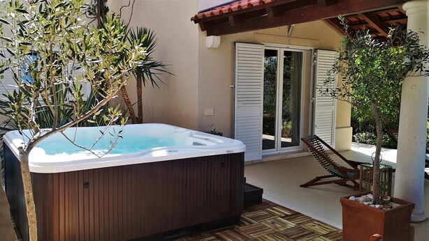 A hot tub in a covered outdoor area with wooden flooring, a patio table, and chairs. - Gumonca in Supetar With 6 Bedrooms and 5 Bathrooms (Supetar)