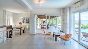 A spacious living area with a dining set, a kitchen area, and a view of a pool. - Gumonca in Supetar With 6 Bedrooms and 5 Bathrooms (Supetar)