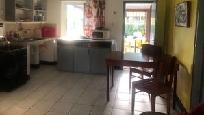 A compact kitchen with a dining area, a microwave on the counter, and a window with floral curtains.