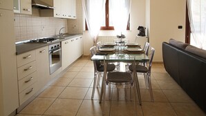 A modern kitchen with a dining area, featuring a glass table, chairs, a sofa, and a stove. - Bellavista Holiday Home (Abruzzo)