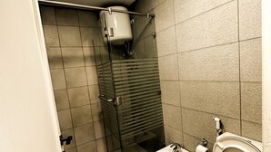 A bathroom with a shower, toilet, bidet, and a towel rack.