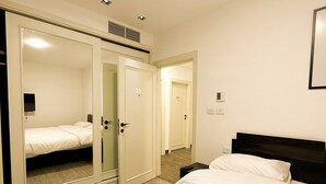 A hotel room with a bed, a wardrobe, and a mirror.