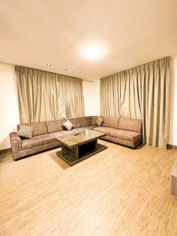 Una sala de estar con un sofá modular, una mesa de centro y cortinas.