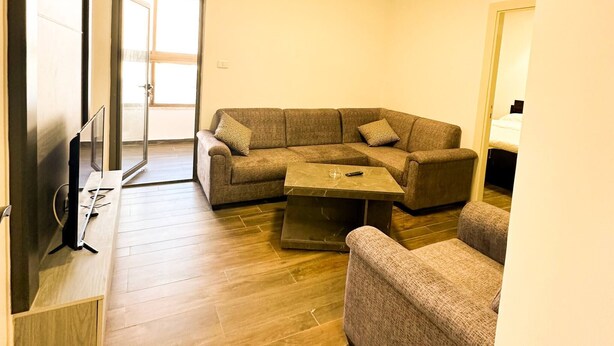 A living room with a sectional sofa, a coffee table, and a flat-screen TV.