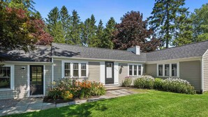 A single-story house with a front porch, a small garden with flowers, and a well-maintained lawn. - Pet Friendly-Fenced Yard-Near Downtown (Skaneateles)