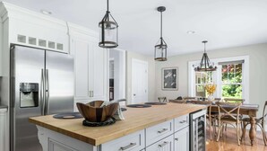 A modern kitchen with white cabinetry, a stainless steel refrigerator, wooden countertops, and pendant lighting. - Pet Friendly-Fenced Yard-Near Downtown (Skaneateles)