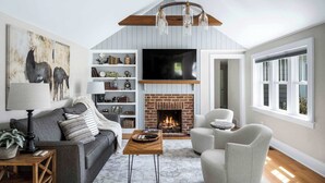 A living room with a fireplace, a sofa, a coffee table, and a TV mounted above the fireplace. - Pet Friendly-Fenced Yard-Near Downtown (Skaneateles)