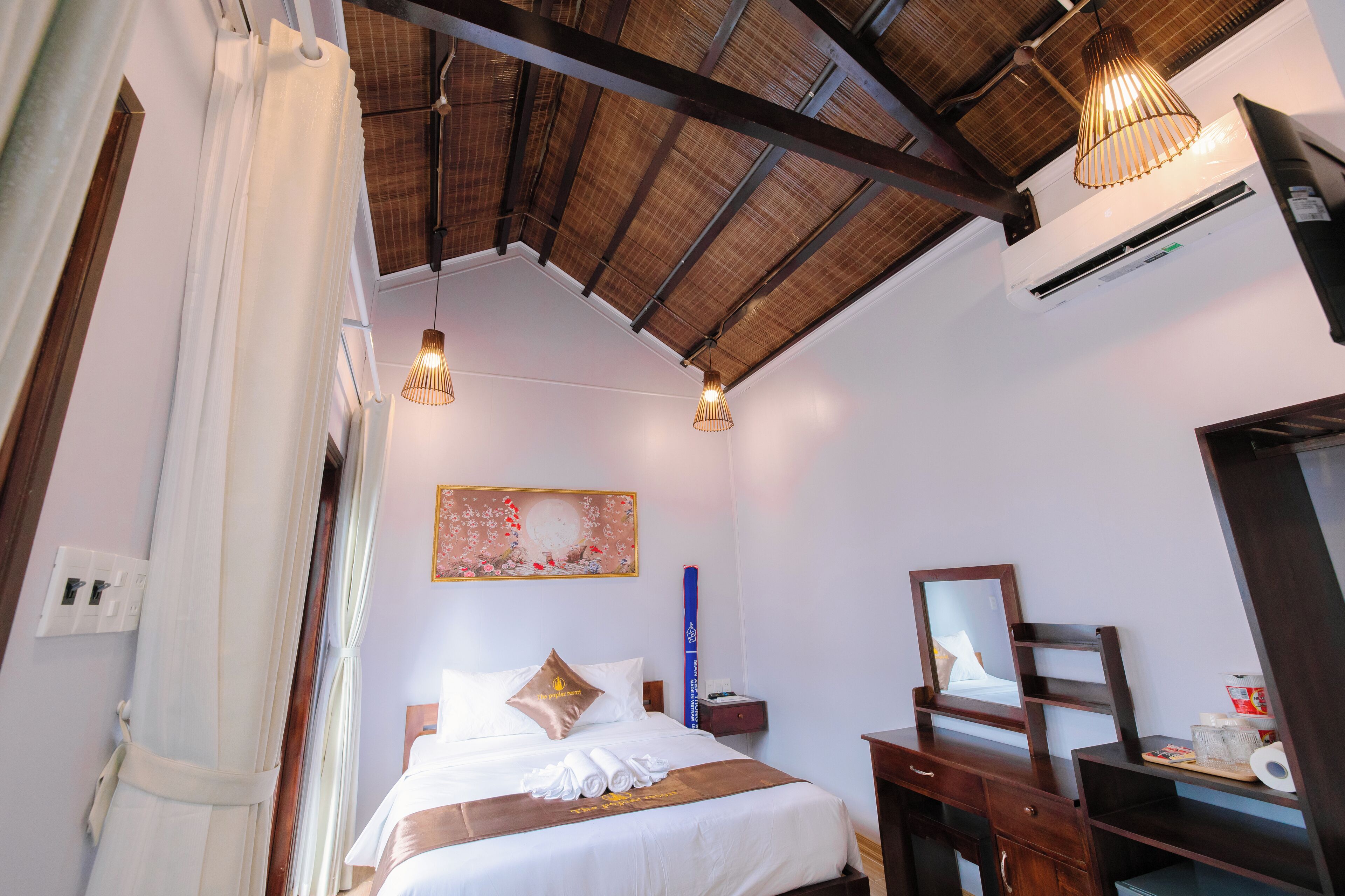 Ein Hotelzimmer mit Bett, Nachttisch, Spiegel und Deckenventilator.