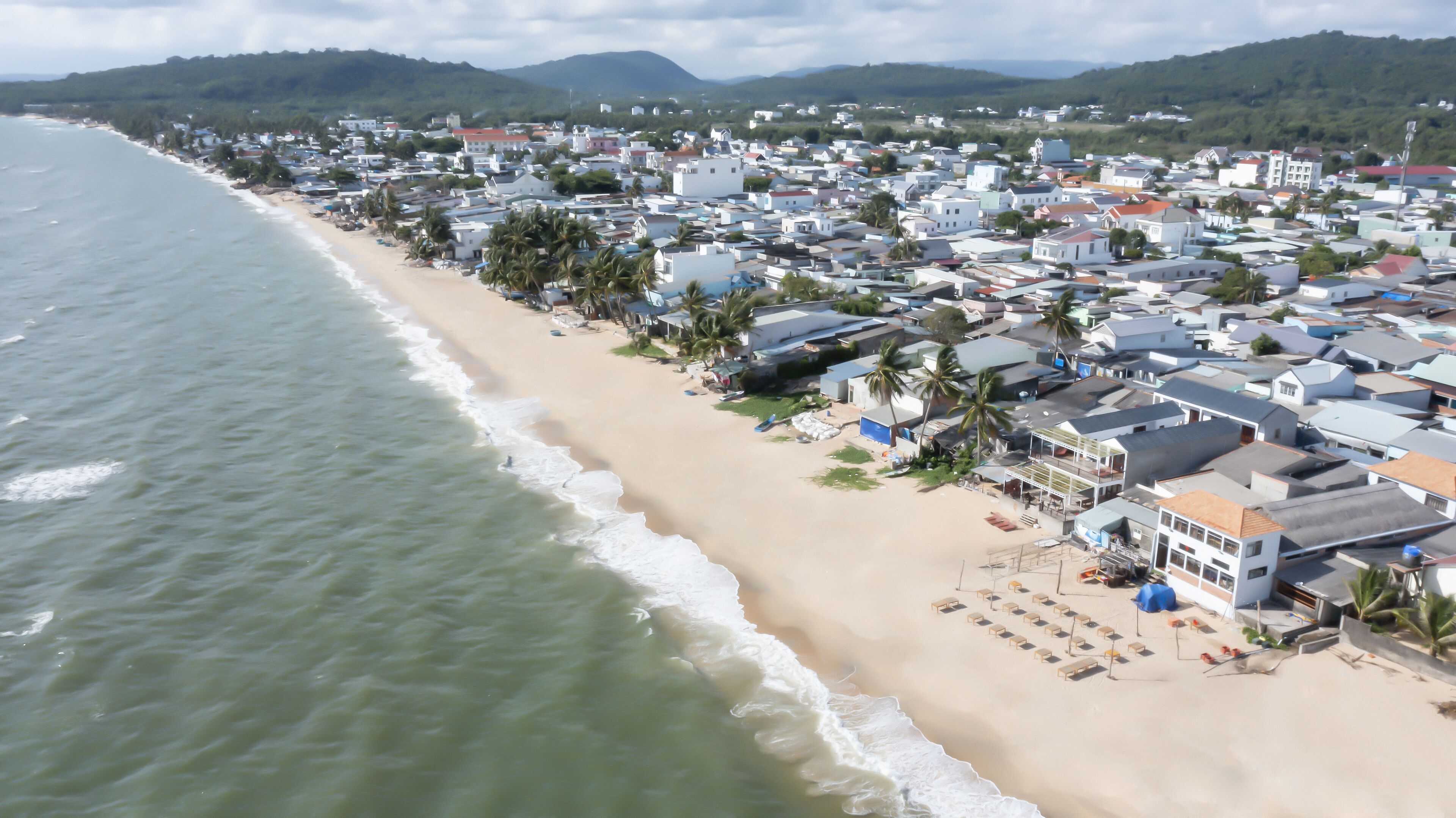 A coastal town with beachfront properties, including houses and villas with balconies, some with attached patios.